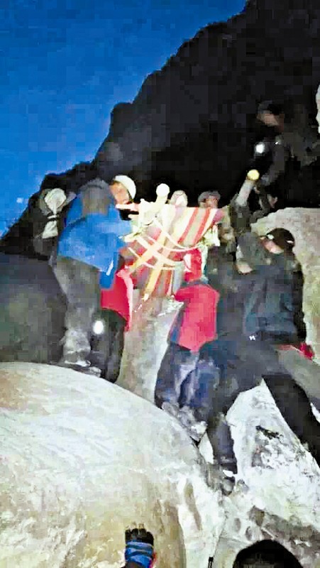 救援隊(duì)員用自制的簡易擔(dān)架抬傷者。