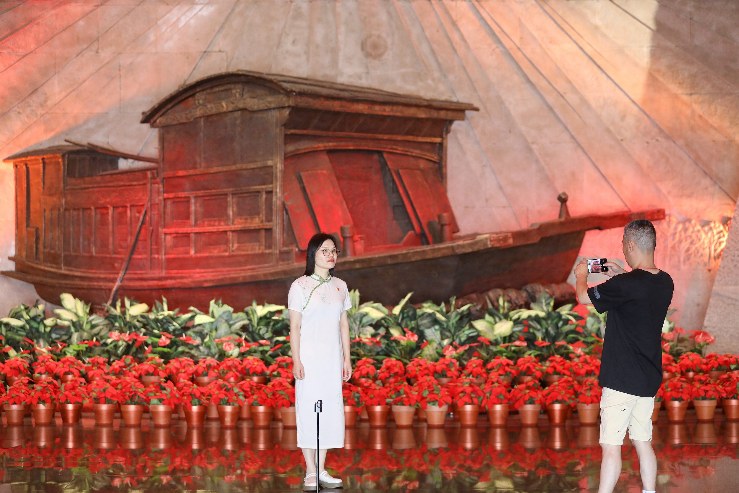 2025年6月24日，浙江嘉興，游客在南湖革命紀(jì)念館與紅船雕塑合影。（圖片來源：視覺中國）